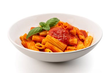 Makarna rigatoni makarna domates soslu ve yeşil fesleğen yapraklı beyaz tabakta, kırpma yolu ile izole edilmiş.