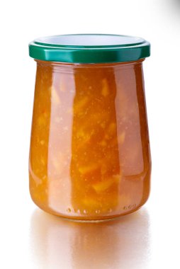 Cam kavanozda turuncu marmelat, beyaz üzerine izole edilmiş yeşil başlık, kırpma yolu da dahil.