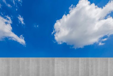 Büyük beyaz bulutlu mavi gökyüzüne karşı beton duvar. Kopyalama alanı olan arkaplan grafik ögesi.