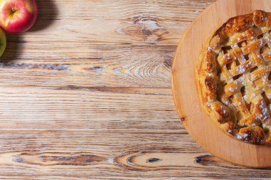 İçinde pudra şekeri serpiştirilmiş çıtır çıtır elmalı turta. Yakınlardaki taze kırmızı elmalar kırsal tarza harmoni ekler.. 