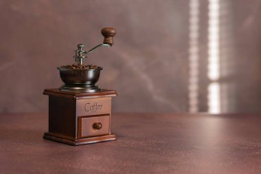 Kahve çekirdekleri ile dolu, içinde kahve çekirdekleri olan klasik ahşap bir el yapımı kahve öğütücüsü. Önüne oyulmuş kahve ve yumuşak ışık sıcak, sıcak bir atmosfer yaratıyor.