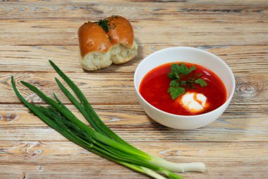 Taze ekmek ve ahşap bir masada yeşil soğan yanında bir tabak sebze ve ekşi krema..