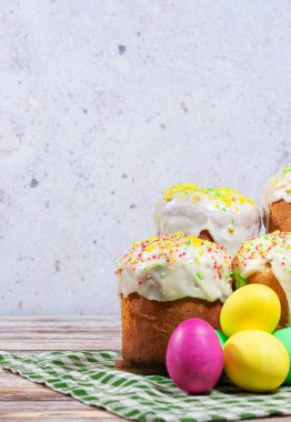 Dört kulich, kar beyazı jöleli ve parlak serpilmiş, yeşil çizgili bir peçetenin arkasında renkli boyalı yumurtalarla çevrili. Tatilin ve bahar geleneklerinin sıcaklığı.