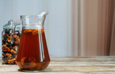 Ev yapımı kurutulmuş meyve, cam sürahide öğütülmüş, kırsal ahşap masada çeşitli meyveler, doğal ışık, rahat mutfak tarzı..