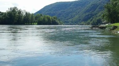 Mali Zvornik, Sırbistan. Banja Koviljaca yakınlarındaki Drina nehri, Sırbistan 'ın BH kıyılarının manzarası. Suyun akışı, nehrin karşı kıyısındaki yeşillik. Güzel tepeler ve dağlar. Yavaş çekim.