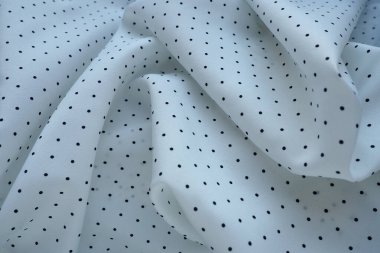 İpek kumaş dokusu. Beyaz arka planda siyah benekler. Hafif sentetik kumaştan beyazlar giyip tekrar tekrar giyin. Tekstil dalgalar ve kıvrımlardan oluşur. Kadınsı klasik biçim