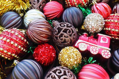 Sarı süslemeli ve Noel toplu Noel arkaplanı. Güzel Noel oyuncakları ve dekorasyonları. Kırmızı, altın, kahverengi, gümüş, sarı çizgili parlak toplar. Oyuncak trenin lokomotifi