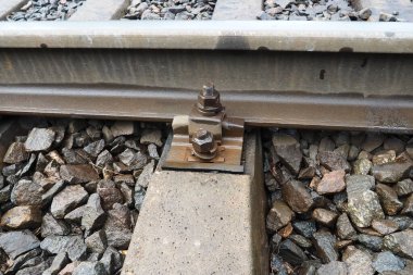 Demiryolları. Metal çelik korkuluklar ve ahşap uykucular. Demiryolunda perçin ve perçin var. Demiryolu raylarının taşlı dolgusu