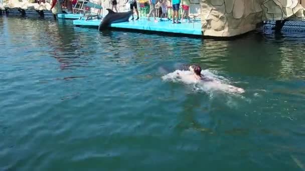2021年6月29日 俄罗斯安纳帕 一个女孩抓住两只宽吻海豚的鳍 在水里游泳 海豚与人类的互动 Crowd People — 图库视频影像