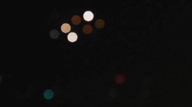 Yeni yılda ya da Noel tatilinde havai fişek ve havai fişeklerden rengini kaybetmiş. Soyut bulanık yuvarlak renkli bokeh. Gece gökyüzünün arka planında Bokeh ışıkları. Siyah arkaplan