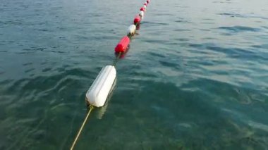 Şamandıra yüzme alanı işareti. Dayanıklı beyaz ve deniz kırmızı diş mineleriyle kaplı görünür kanal işaretleyicisi, dayanıklılığı arttırmak için. Bariyerler ve yüzme alanları oluşturuluyor. Sudaki şamandıralar, Adriyatik Denizi, Karadağ