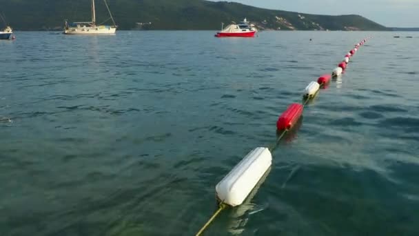 2022年8月13日 モンテネグロ メルジネ ボート ヨットが海に浮かぶ ブイはエリアマーカーを泳ぐ 耐久性を向上させるために耐久性のある白とマリンレッドエナメルでコーティングされた可視チャネルマーカー — ストック動画