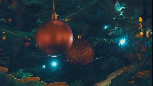 新年快乐圣诞树装饰与红玻璃球在树枝上 家里放假时 旁边闪烁着的灯泡的茶壶装饰着花环 节日气氛 从纸张和织物上剪下的弓形和花纹 — 图库视频影像