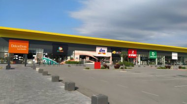 Stop shop shopping center, Sremska Mitrovica, Serbia, June 06, 2022. Square with open shops dm, intersport, dekordom, ccc, lc waikiki. People, parking and pavement. Sunny summer day.