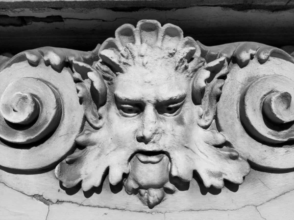 Decorative detail on the facade. Relief on the facade of a building. Stucco molding in the form of a man\'s head with curly hair, mustache and curls on the sides. High relief concrete bas-relief