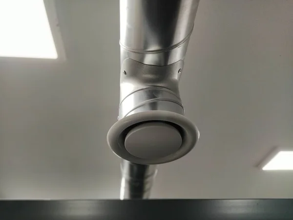 公共卫生间的引擎盖 圆形金属管 带有灰度空气萃取器 工程通风系统 房间天花板下的镀锌管子 塑料圆头 — 图库照片
