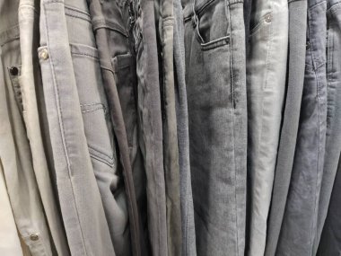 Elbiseler askılarda asılı. İkinci el mağazasının çeşitli ürünleri. Giysiler askıda asılı, müşterilere satılmaya hazır. Krizde para biriktiriyorum. Ucuz alışveriş. Pantolon ve pantolon.