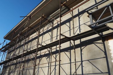 Tek katlı yeni bir evin iskelesi. Cephe işe yarıyor. İşçilik binası. Düşük katlı özel bina. Bir binanın duvarını alçılıyor. Dükkan binası. Metal üretim yapıları