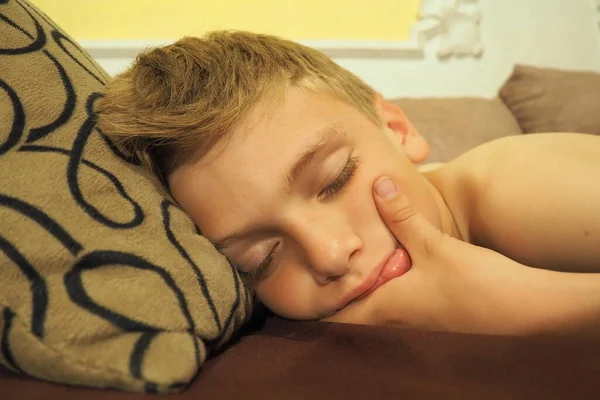 10 year old Caucasian boy fell asleep on the couch. Childrens dream. Sleep problems, falling asleep, insomnia, fatigue. The concept of health, mode of wakefulness and rest, education and prevention