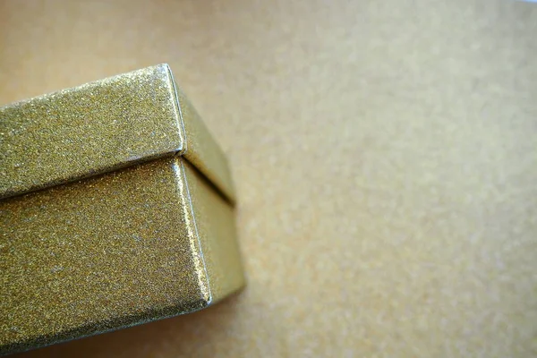Golden gift box on a golden background. Decorative surprise box. Copy space.