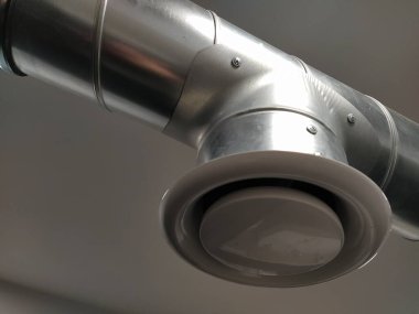Umumi tuvalette çıkarıcı kaput. Gri hava çıkarıcılı yuvarlak metal boru. Mühendislik havalandırma sistemleri. Odanın tavanının altındaki galvanize borular. Plastik yuvarlak uç.