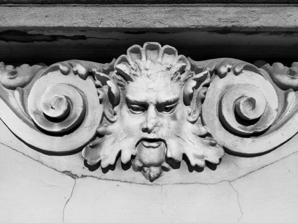 Decorative detail on the facade. Relief on the facade of a building. Stucco molding in the form of a mans head with curly hair, mustache and curls on the sides. High relief concrete bas-relief