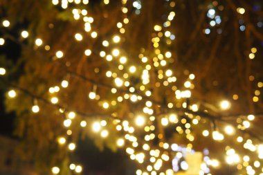 Kutlama çelengi. Şehir gece lambası bulanık Bokeh, odaklanmamış arka plan. Noel şakası. Karanlık gökyüzüne karşı güzel ışıklar. Yılbaşı ve Noel için sokak dekorasyonu.