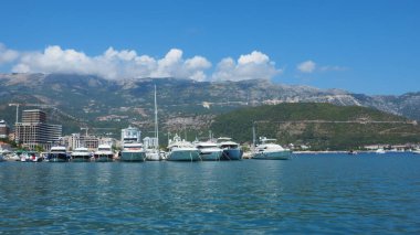 Budva, Karadağ, 15 Ağustos 2022 Adriyatik denizi, kıyı, dağlar, deniz dalgaları. Tekneler ve gemiler sete demirlediler. Su taşıma aracı. Turistik su aktiviteleriyle yaz tatili gezileri.