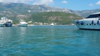 Budva, Karadağ, 15 Ağustos 2022 Adriyatik denizi, kıyı, dağlar, deniz dalgaları. Tekneler ve gemiler sete demirlediler. Su taşıma aracı. Turistik su aktiviteleriyle yaz tatili gezileri.