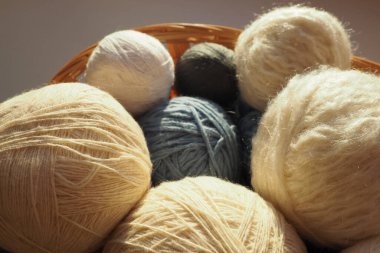 White, beige and blue woolen and acrylic threads wound into a ball or skein. Several skeins of light yarn in a basket. Knitting as a hobby. A clew of thread clipart