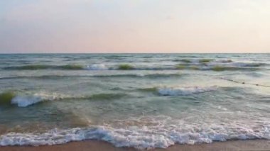 Sakin dalgalar kumlu sahilde yuvarlanıyor. Denizde ya da okyanusta gün batımı. Su hareketi. Dalgalar köpürüyor. Turist cenneti. Kum deniz suyundan görülebilir. Karadeniz 'de plaj tatili.