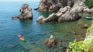 Dubrovnik Hırvatistan ve Adriyatik Denizi 08.14.2022 Turist dalgalarda kayak yapıyor. İnsanlar rahatlar ve deniz yolculuklarından hoşlanırlar. Rocky Sahili. Tekne kayaya doğru yüzüyor. Güneş ışınları. Su altı bitkileri ve algler