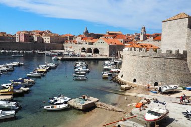 Dubrovnik, Hırvatistan, 14 Ağustos 2022. Yazın şehir limanı, turistik eğlence. Turistler yürür, teknelere ve gemilere biner ve tekne gezilerine çıkarlar. Adriyatik Denizi. Yerel sakinlerden biri bir köpekle oynuyor. Eski kaleler