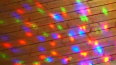 Christmas or New Year laser light show on a wooden wall indoors. Festive or disco lighting. Multi-colored light reflections of red, blue, green and purple run across the surface. Light projector