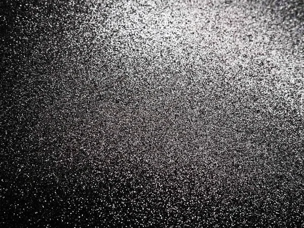 Black glitter texture christmas background. Bent shiny velvet paper.