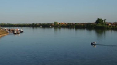 Macvanska Mitrovica, Sırbistan, Balkanlar, 10 Ekim 2022. Sava nehri akıyor. Rüzgarsız sakinlik. Sürat teknesi suda yüzüyor. Balıkçılık ve akşam nehir yürüyüşü. Sremska Mitrovica. Su nakliyesi yolu