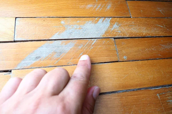 stock image Old, scratched parquet flooring needs maintenance. the parquet is damaged by scratches from prolonged use. Masters hands show damage to the floor.