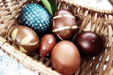 Easter boiled eggs of different colors dyed with onion peel and paint in wicker basket. Vegetable patterns on the shell. Traditional festive coloring of eggs. Wicker basket