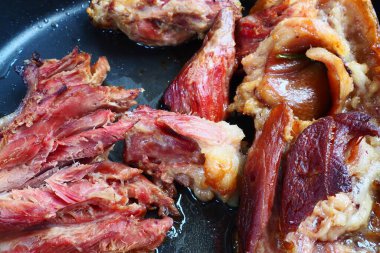 Roasted smoked pork shoulder or knee. Delicious meat on a black baking sheet with drops of vegetable oil, taken out of the oven. Pork delicacy for dinner in a restaurant and family lunch. Red meat.