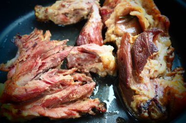 Roasted smoked pork shoulder or knee. Delicious meat on a black baking sheet with drops of vegetable oil, taken out of the oven. Pork delicacy for dinner in a restaurant and family lunch. Red meat.
