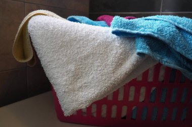 Çamaşır sepetindeki havlular. Mavi ve pembe pamuklu havlu pembe bir plastik sepete atılır. Oda servisi. Çamaşırları yıkamadan önce depolamak ve ayırmak. Yukarıdan açık bir pencereden gelen ışık