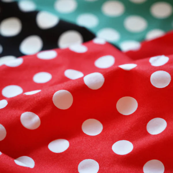 White polka dots on red pink background, textile fabric surface background. Green polka dot. Two layers of wrinkled material