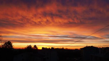 Güzel sarı turuncu kırmızı şafak ve sabah gündoğumu. Şehir ufkunun üzerinde güneş diskinin yükselişi. Yükselen güneş ve bulutlar. Güneş diskini kaldırma süresi 4K. Şehir manzarası. Sremska Mitrovica, Sırbistan