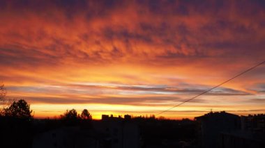 Güzel sarı turuncu kırmızı şafak ve sabah gündoğumu. Şehir ufkunun üzerinde güneş diskinin yükselişi. Yükselen güneş ve bulutlar. 4K güneş diskini kaldırıyor. Şehir manzarası. Sremska Mitrovica, Sırbistan