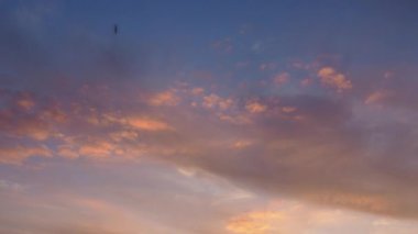 Sirus ve kümülüs bulutları batan güneş tarafından aydınlatılır ve sarıya, kırmızıya, pembeye dönüşür. 4K hızlandırılmış videoda rengarenk bulutlar değişiyor. Güzel gün batımı. Zaman aşımı.