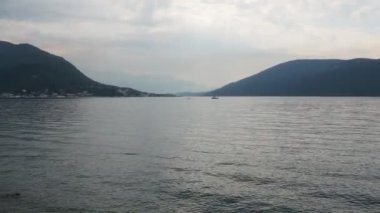 Herceg Novi, Karadağ. Deniz kıyısı tatili. Deniz gezileri. Adriyatik Denizi 'nde tekneler yüzer. Akdeniz seyahat işi. Yelkenliler ve dağlar. Tuzlu suda küçük dalgalanmalar. Dalgalarda gökyüzü yansıması