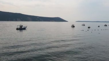 Herceg Novi, Karadağ. Deniz kıyısı tatili. Deniz gezileri. Adriyatik Denizi 'nde tekneler yüzer. Akdeniz seyahat işi. Yelkenliler ve dağlar. Tuzlu suda küçük dalgalanmalar. Dalgalarda gökyüzü yansıması.