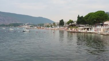 Herceg Novi Montenegro 08.09.2022 Deniz Tatili. Adriyatik Denizi 'nde tekneler yüzer. Akdeniz seyahati. Yelkenliler, dağlar. Sudaki dalgalar. İnsanlar yüzer, güneşlenir ve şehir sahillerinde eğlenir..