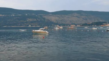 Igalo, Herceg Novi, Karadağ. Deniz tatili. Adriyatik Denizi 'nde tekneler yüzer. Akdeniz seyahat işi. Oteller ve binalar. Igalo yolu. Dağdaki ormanda yangın ve duman. Suda şamandıralar.