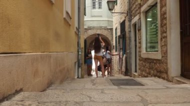 Herceg Novi, Karadağ, eski kasaba, Sat-kula kulesi, Sahat-kula, Tora, şapel kulesi, Saat Kulesi 08.09.22 Şortlu bir kız telefondaki kuleyi fotoğraflıyor. İnsanlar ve çocuklar eski cadde boyunca yürür